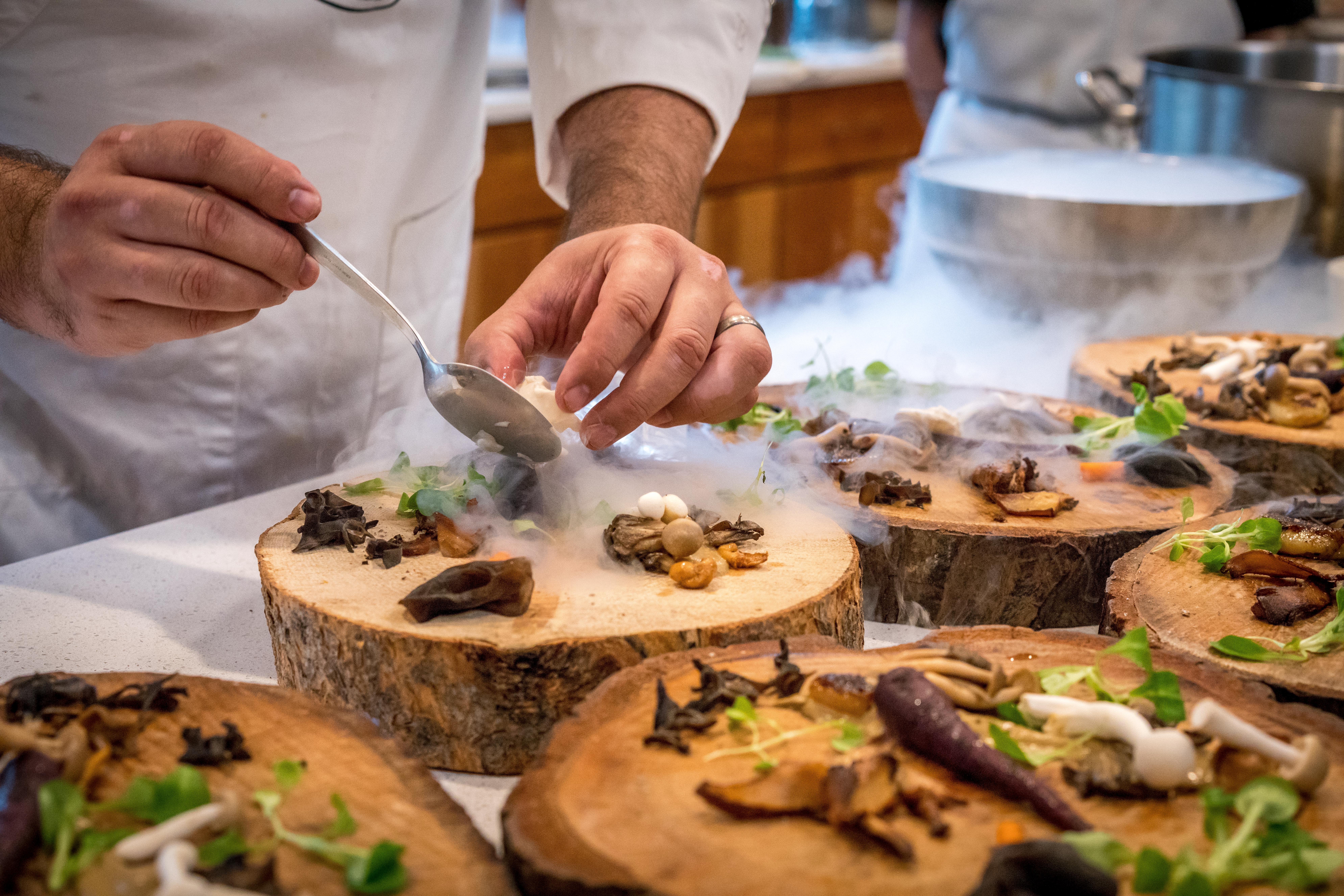 chef plating on wood rounds at an upscale restaurant